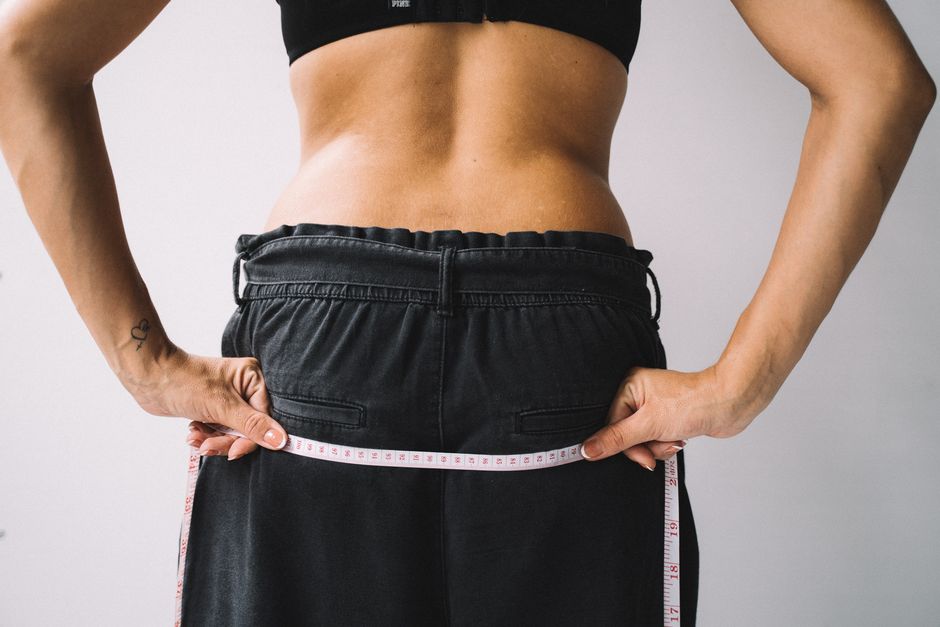 Woman measuring her waist to track weight loss progress